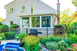 Vue extérieure d’un solarium trois saisons Sunspace avec un jardin fleuri et verdoyant