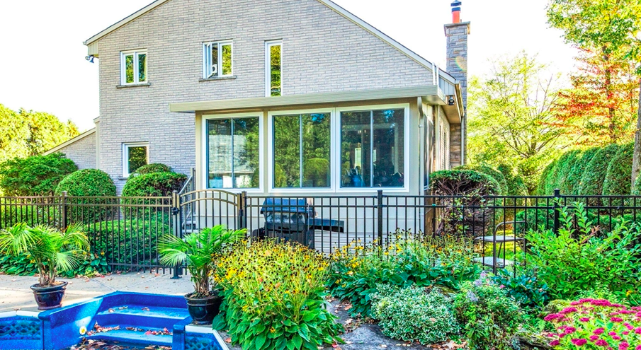 Vue extérieure d’un solarium trois saisons Sunspace avec un jardin fleuri et verdoyant